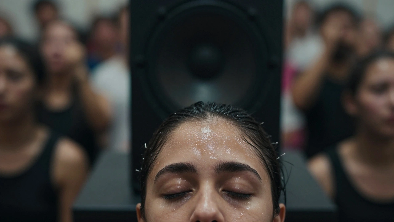 Sweat on a dancer's forehead as bass speakers vibrate behind them.