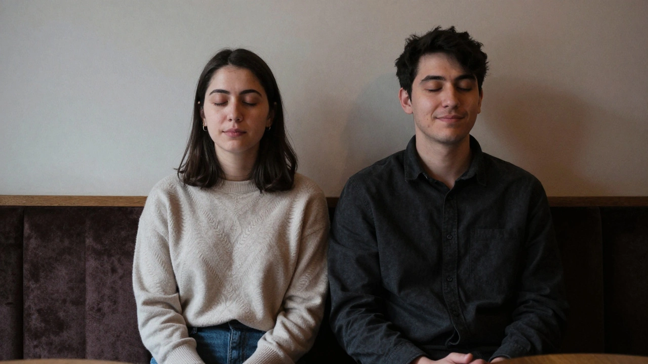 Two people sitting quietly together, eyes closed, smiling in a cozy lounge.